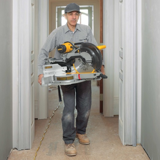 12 inch double bevel sliding compound miter saw being carried by a worker at a worksite.